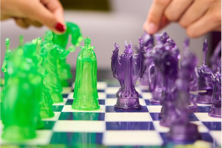 hands grabbing green and purple chess pieces