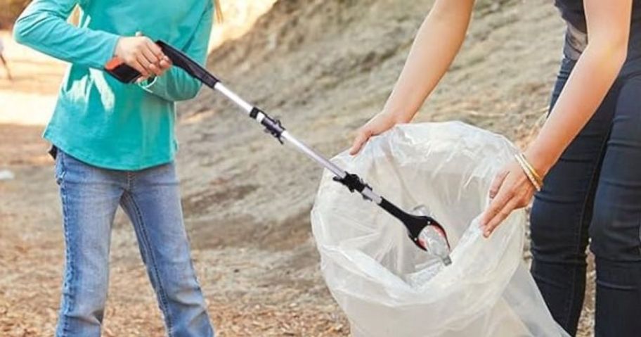 kid using foldable grabber to put trash into bag