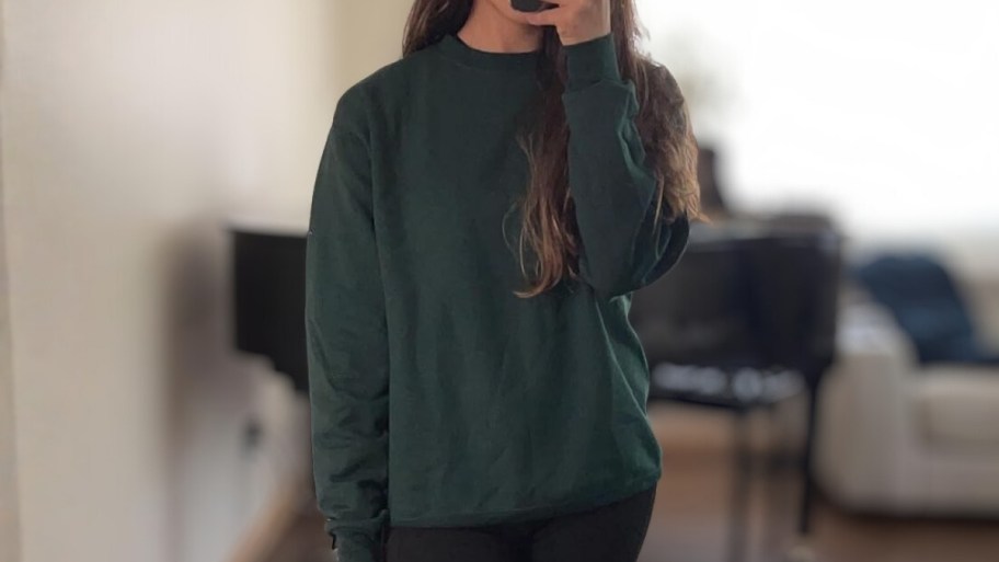 a woman in a dark green sweatshirt taking a selfie