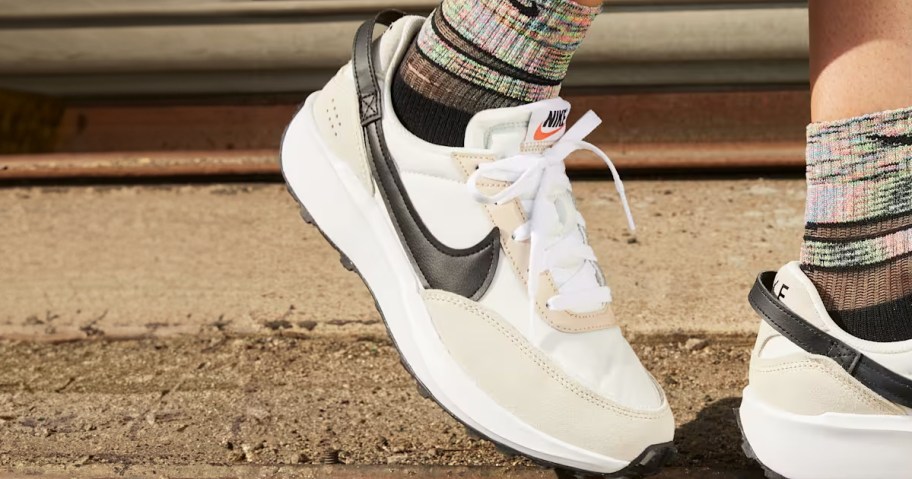 person wearing tan, white and black nike shoes 
