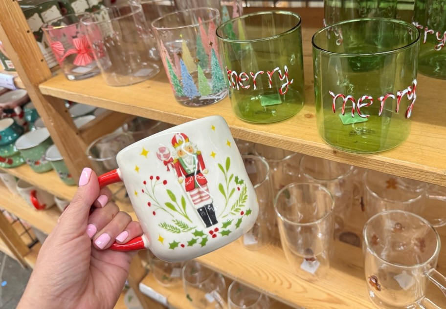 a womans hand holding a nutcracker ceramic mug