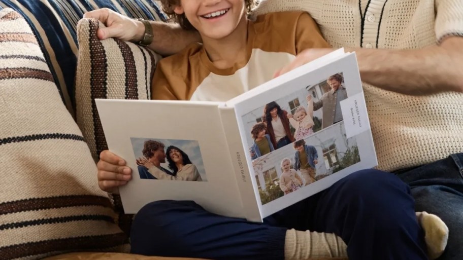 a kid looking thru a photo book with dad. 