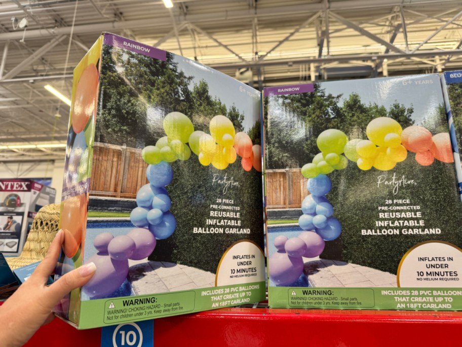 hand touching a box containing a resuable balloon arch sitting on a store shelf
