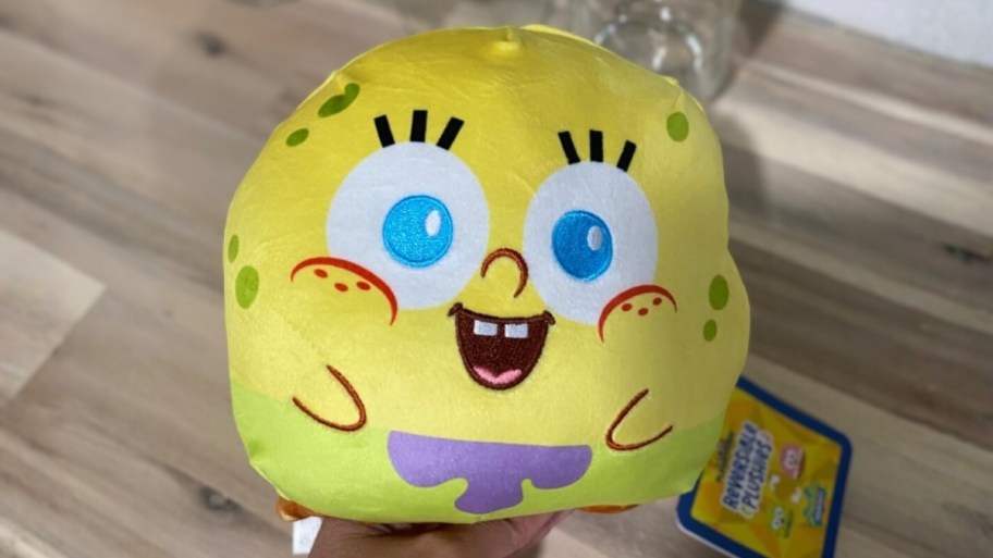 a hand holding a spongebob reversible plush