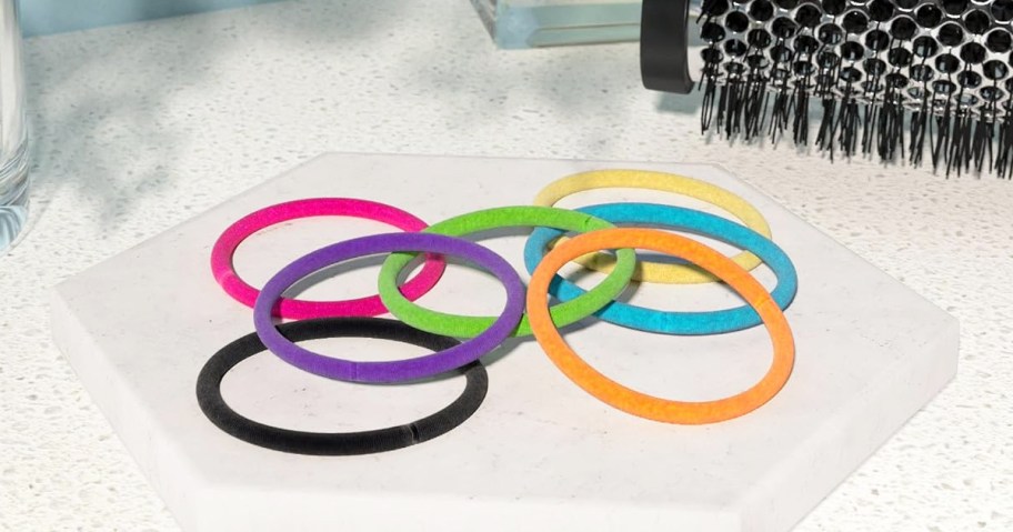 colorful hair elastics near a round hair brush