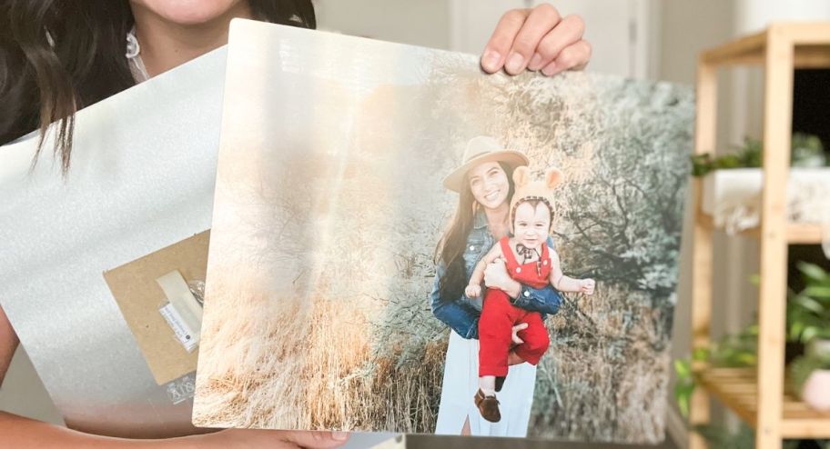 woman holding two metal frames with pictures of her children