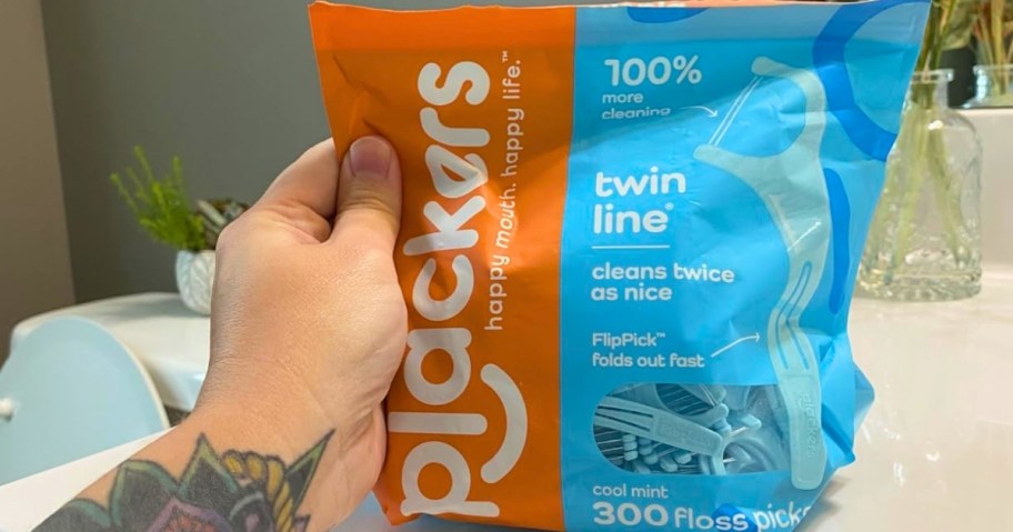 person holding bag of plackers twin line floss picks in cool mint