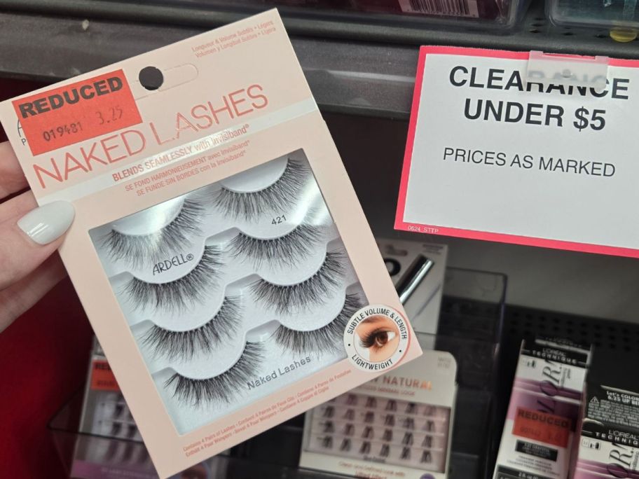 Hand holding a pack of fake lashes next to a clearance Under $5 sign at Sally Beauty Supply