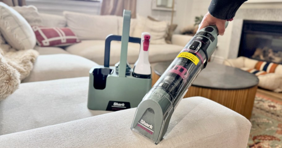 person using a Shark StainForce cleaner on the arm of a couch