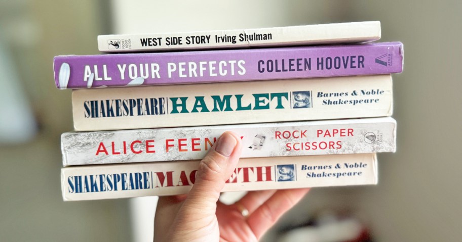 hand holding up a stack of books
