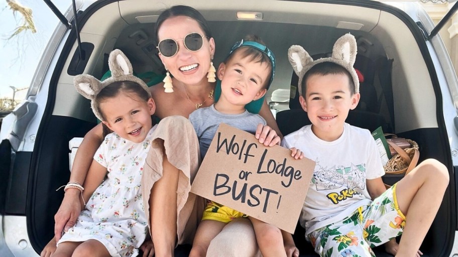 family sitting in truck holding wolf lodge or busy sign