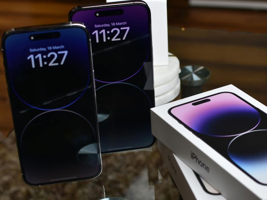 New iphones on a table next to the boxes they came in