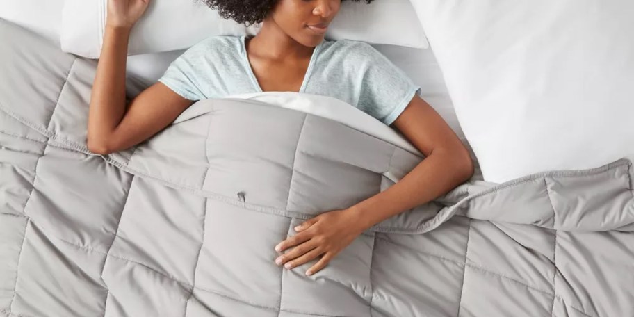 woman laying down with gray blanket on bed 