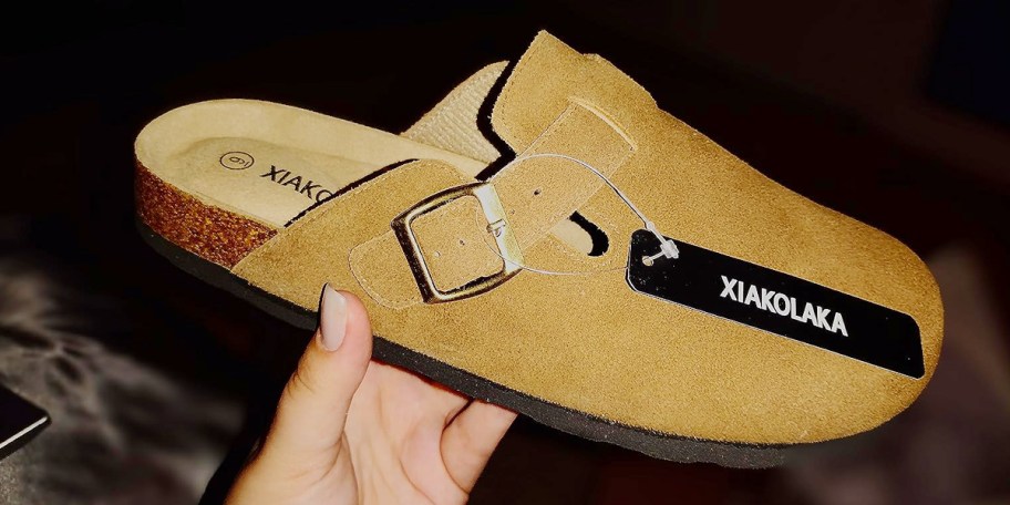 hand holding tan clogs 