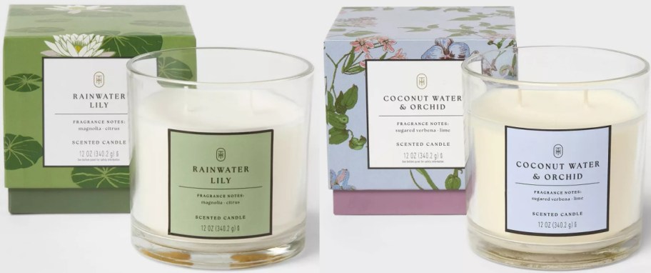 Two scented candles in clear jars with matching floral packaging. One is "Rainwater Lily" with green box; the other "Coconut Water & Orchid" with blue box.