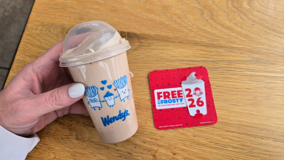 hand holding a wendys frosty next to the wendys frosty key tag