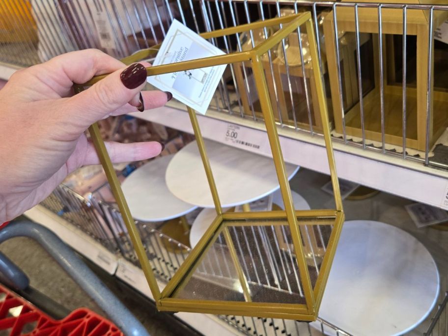 Hand holding a gold metal flower stand from Target's Bullseye's Playground