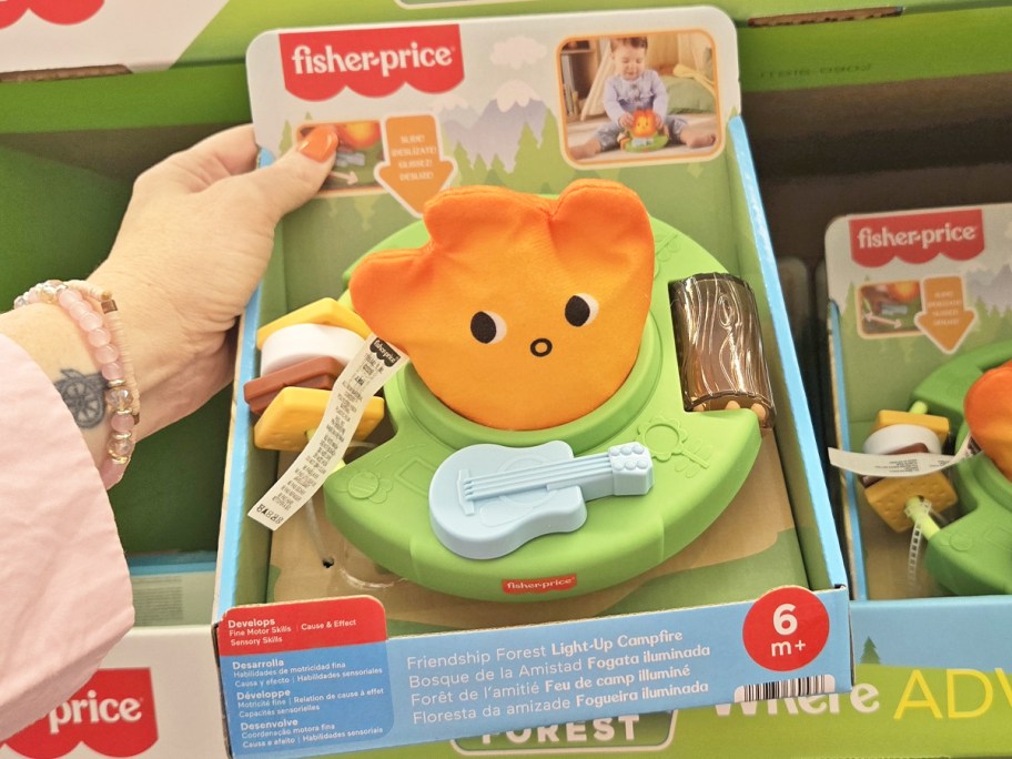 hand holding up Fisher-Price Friendship Forest Light-Up Campfire toy in store