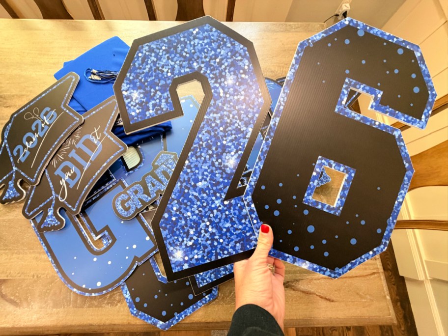 hand holding up blue & black grad sign yard, decor