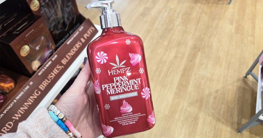 hand holding a pink bottle of Hempz Holiday Body Moisturizer in store