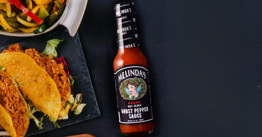 5oz bottle of melinda's ghost pepper hot sauce with tacos and fajitas to the side