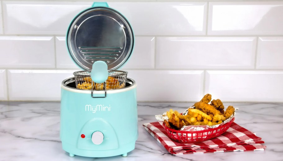 blue mini deep fryer on counter near plate of fries and chicken tenders