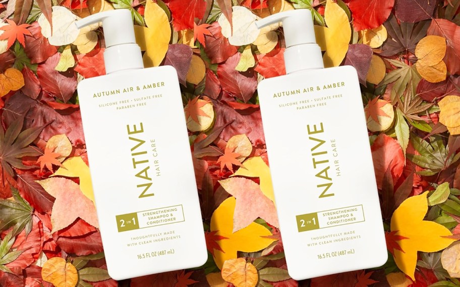 two white bottles of Native 2-in-1 Shampoo & Conditioner in fall leaves