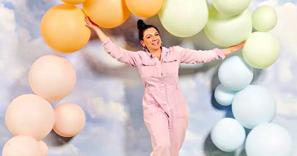 Woman holding up, reusable balloon arch in several different colors