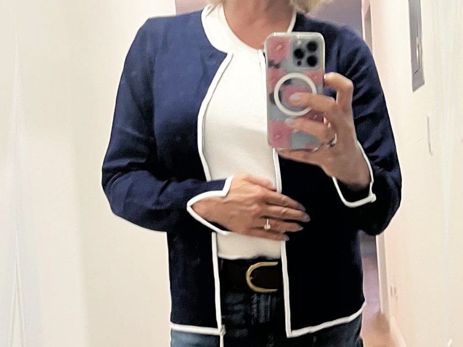 woman taking photo in mirror wearing blue and white sweater