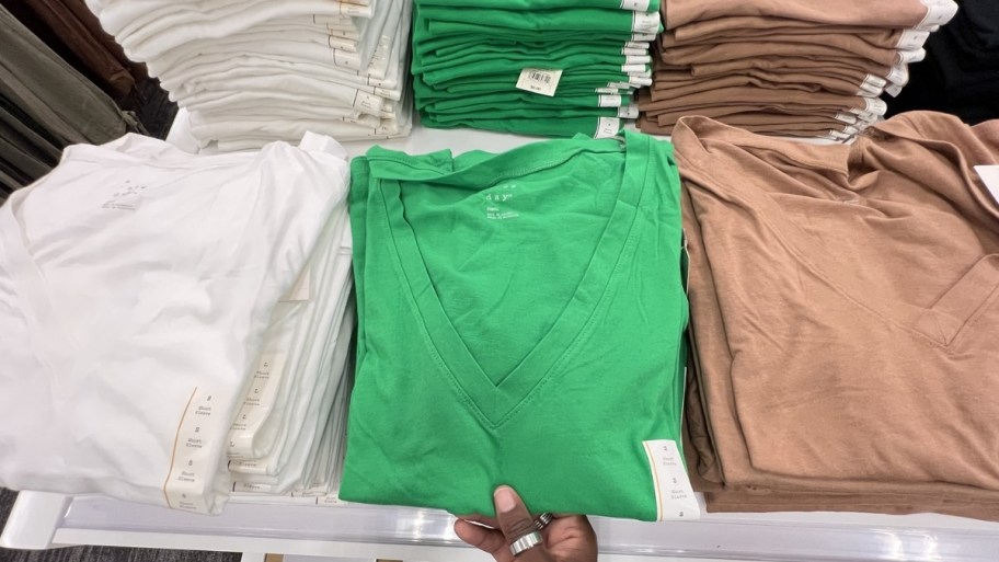 a womans hand reaching for a tee on a display table