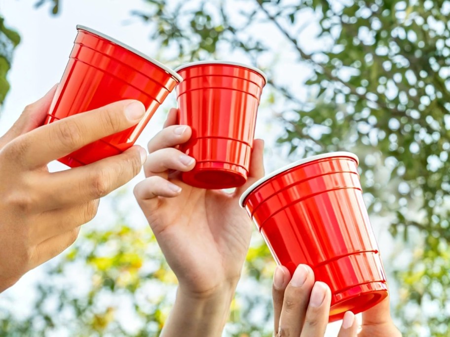 hands holding red plastic cups