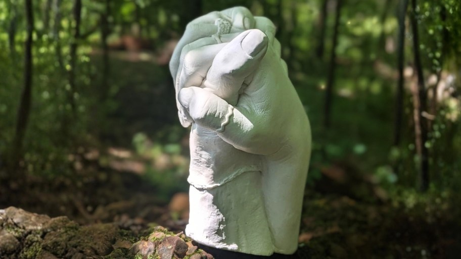 a pair of plaster cast hands on a tree stump