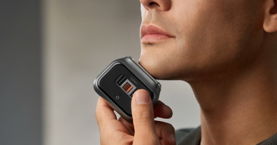 man using an electric shaver on his face