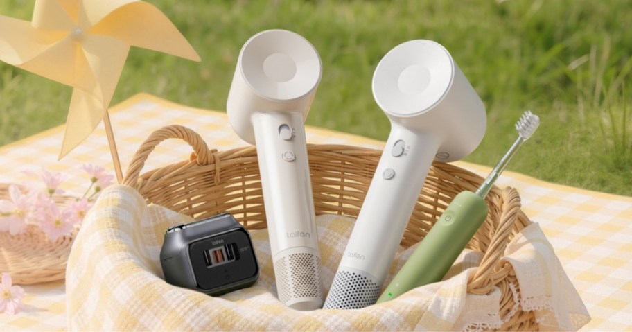 hairdryer, shaver, and electric toothbrush in a basket on a picnic cloth