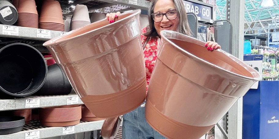 woman holding two round cotta planters 