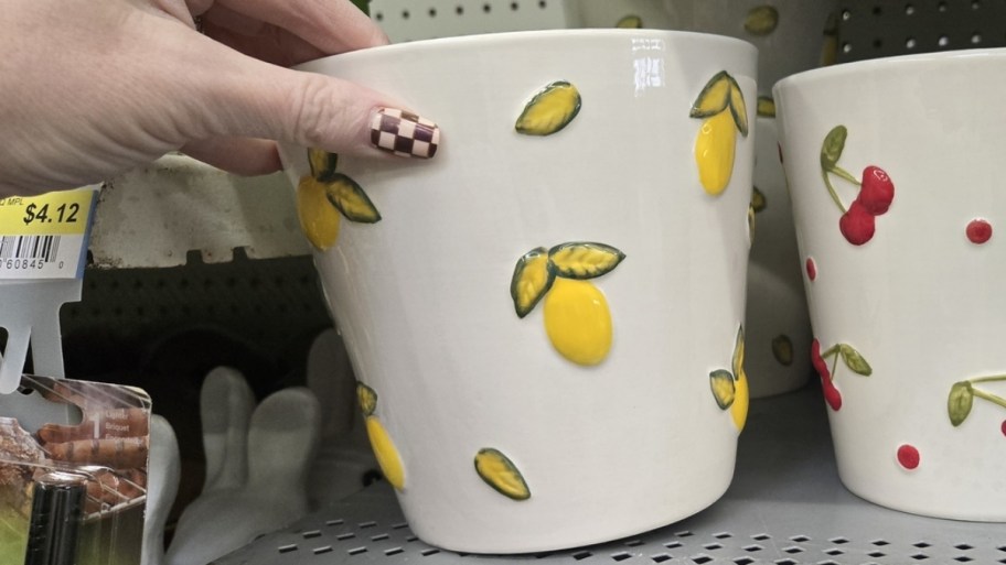 womans hand reaching for a round white planted with lemon print