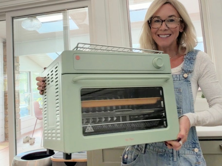 woman holding a mint green our place wonder oven