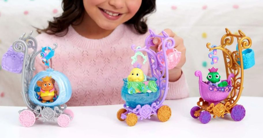 child playing with three different disney Carriages