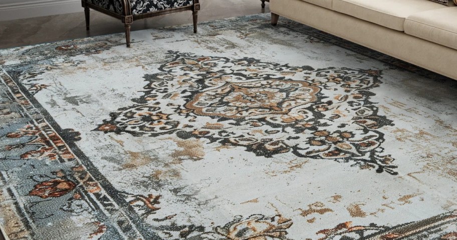 a green, tan, cream, orange, and gold oriental rug in a living room