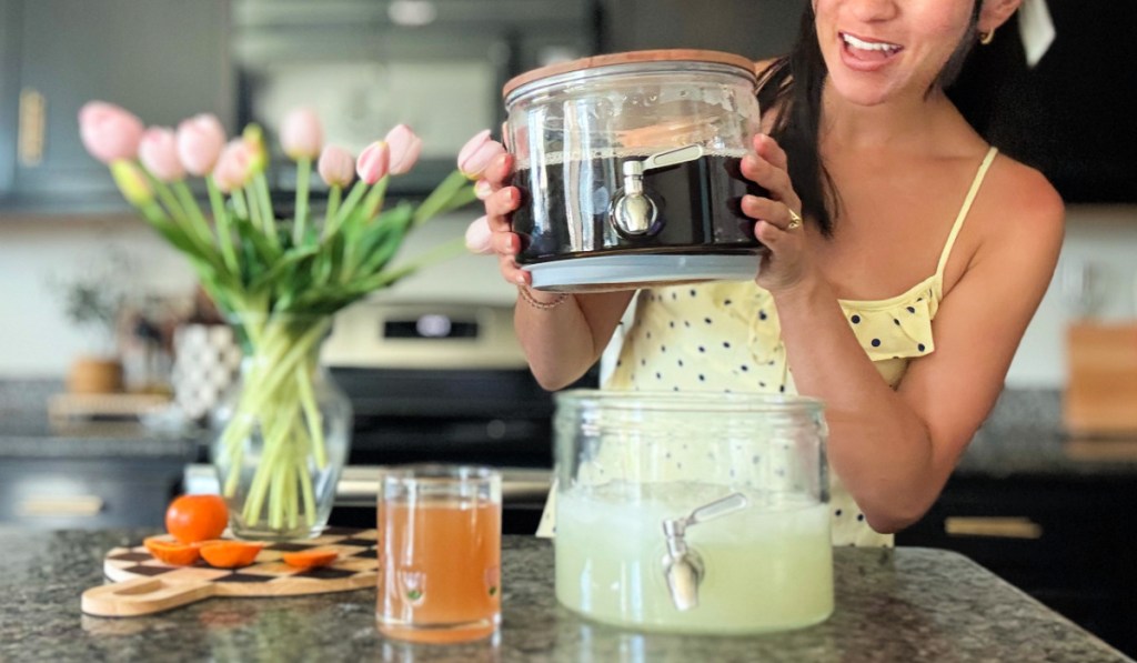 Woman holding glass beverage dispenser