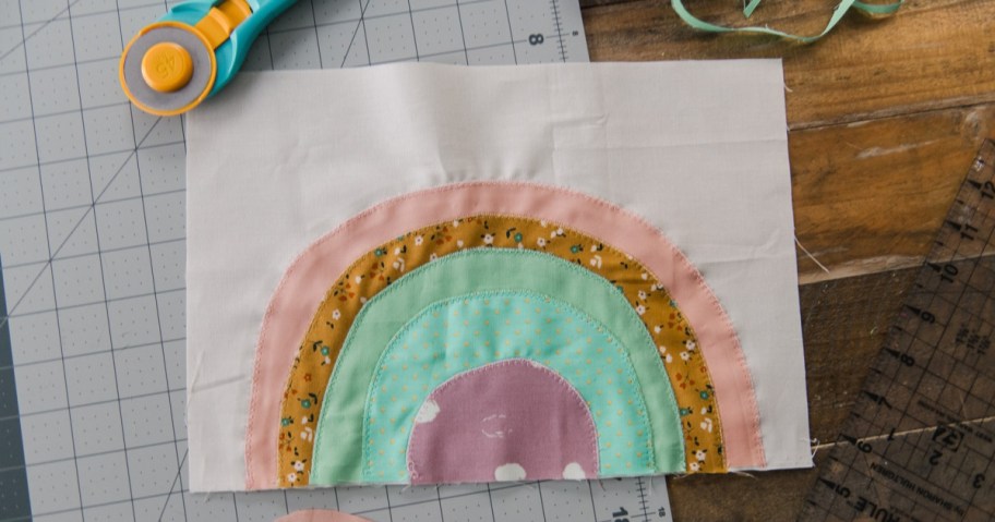 fabric scraps sewn into a rainbow pattern and a cutter
