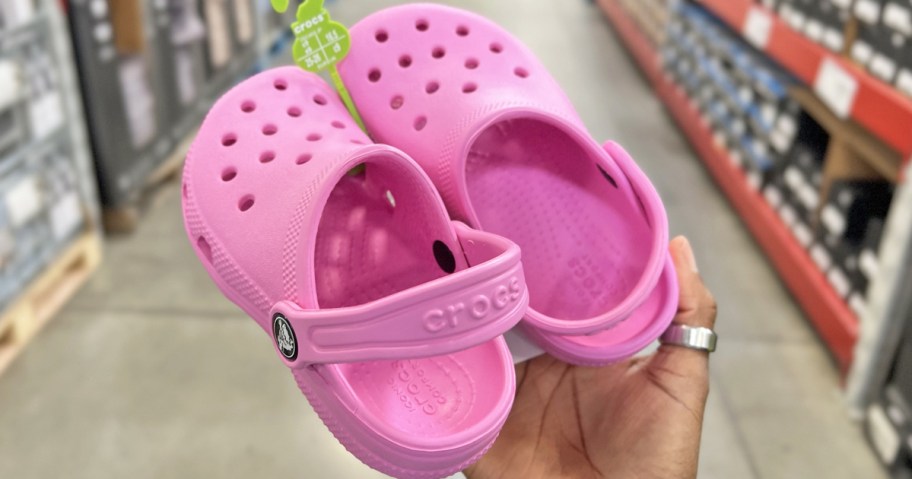 hand holding a pink pair of crocs clogs in store