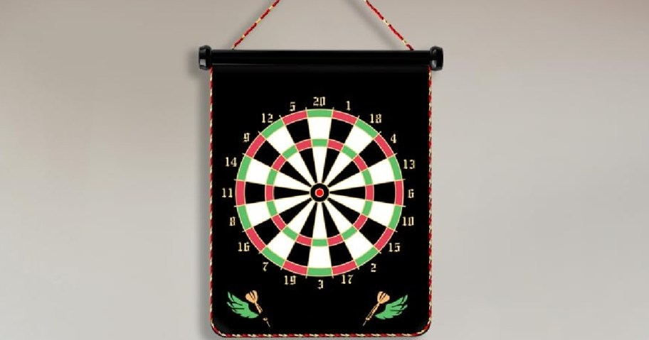 Hanging black dartboard with red, white, and green sections, featuring numbers 1-20. Decorative darts and leaves are at the bottom corners.