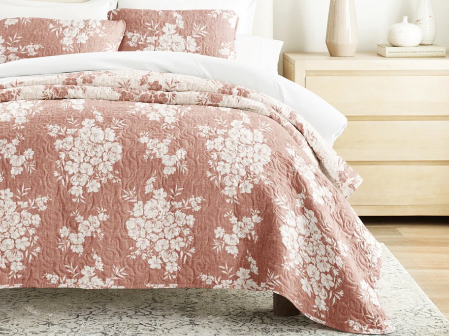 pink and white quilt and pillow shams on bed