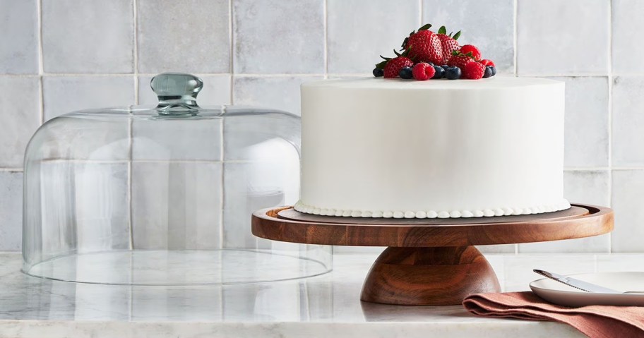 cake on a wood cake stand with glass dome in background