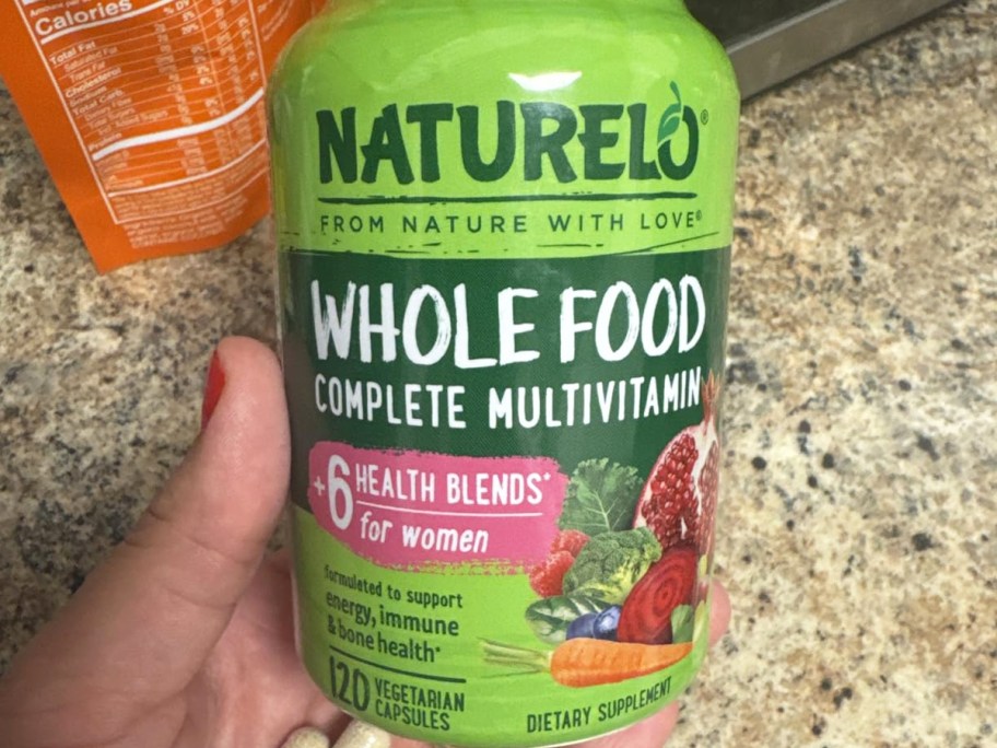 hand holding a green bottle of NATURELO Women's Multivitamins