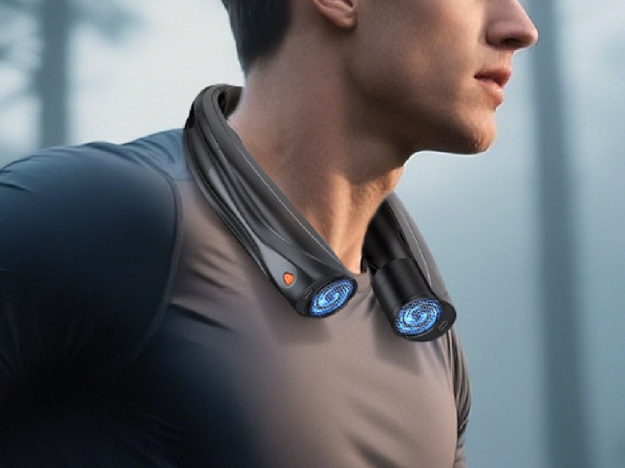 A man is jogging outdoors, wearing a high-tech, black neck fan with blue lights.