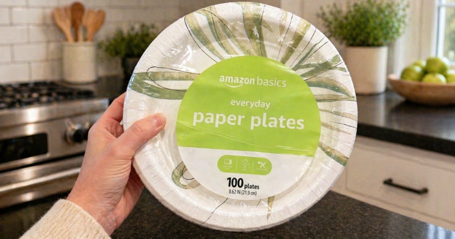hand holding a pack of Amazon Basics paper plates