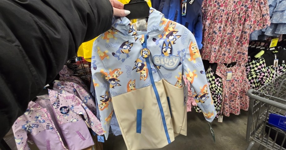a womans hand holding a kids rain jacket