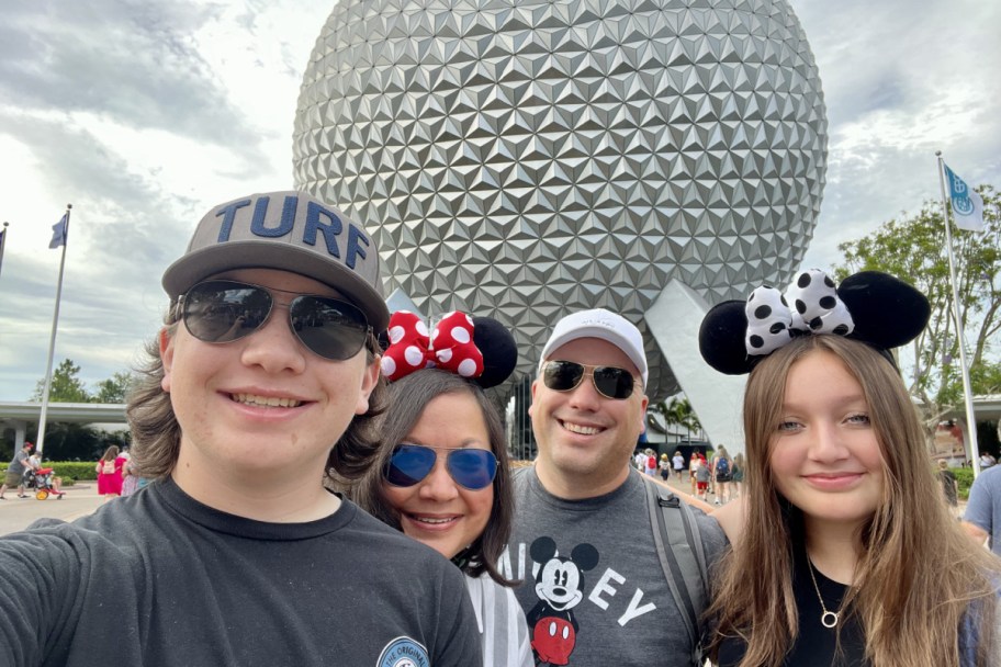 four people in front of giant globe